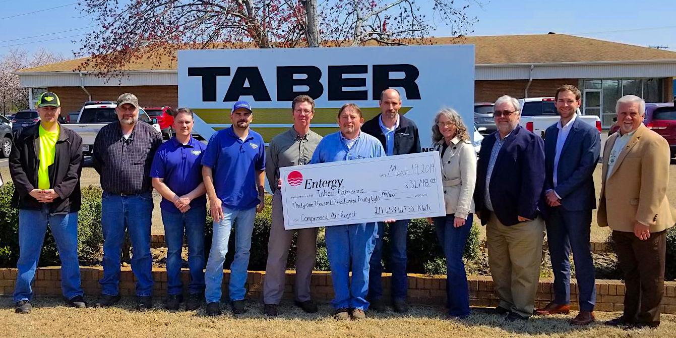 Taber Extrusions staff alongside members from Entergy Incentive Program, CLEAResult, and Arkansas Industrial Machinery, being presented a large rebate check for energy savings.