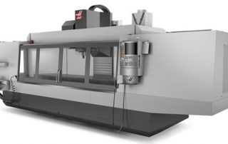 A digital image of a VF-12 CNC machine made by Haas, which is a long rectangular box with four large connected viewing panels to allow operators to see the interior where a vertical column holds a spindle which is used to create aluminum extrusions.