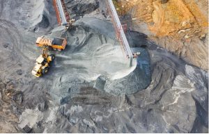A birds-eye-view shot of a mine where tuck is being loaded with silver extraction fed by a belt.