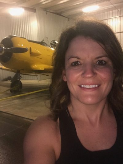 Taber Extrusions' In Focus employee Shae Bradley standing in front of yellow plane