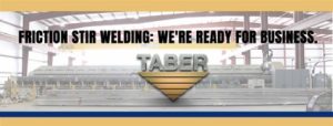 Taber Extrusions friction stir welding line in Russellvile, Arkansas and the words, “FRICTION STIR WELDING: WE’RE READY FOR BUSINESS” and Taber’s official inverted gold triangle logo.