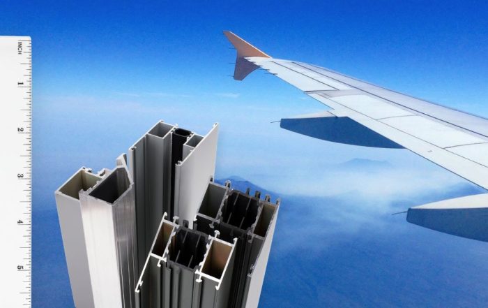 Close-up of a plane wing in the sky with aluminum extrusion profiles aligned to a ruler, highlighting ultra-precision, scalable, lightweight aerospace manufacturing.